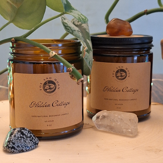Hidden Cottage 8 oz beeswax candle in amber glass jar with metal lid, natural wood wick, pine, cedarwood, and smoky firewood fragrance for grounding and cozy ambiance