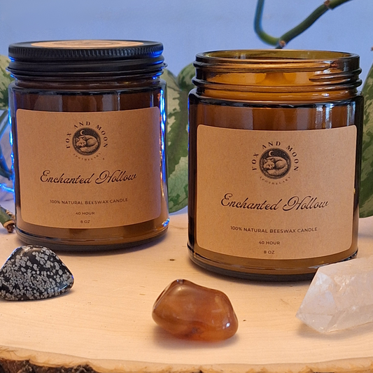 Enchanted Hollow 8 oz beeswax candle in amber glass jar with metal lid, natural wood wick, earthy woodland fragrance of citrus, moss, cedar, and sandalwood